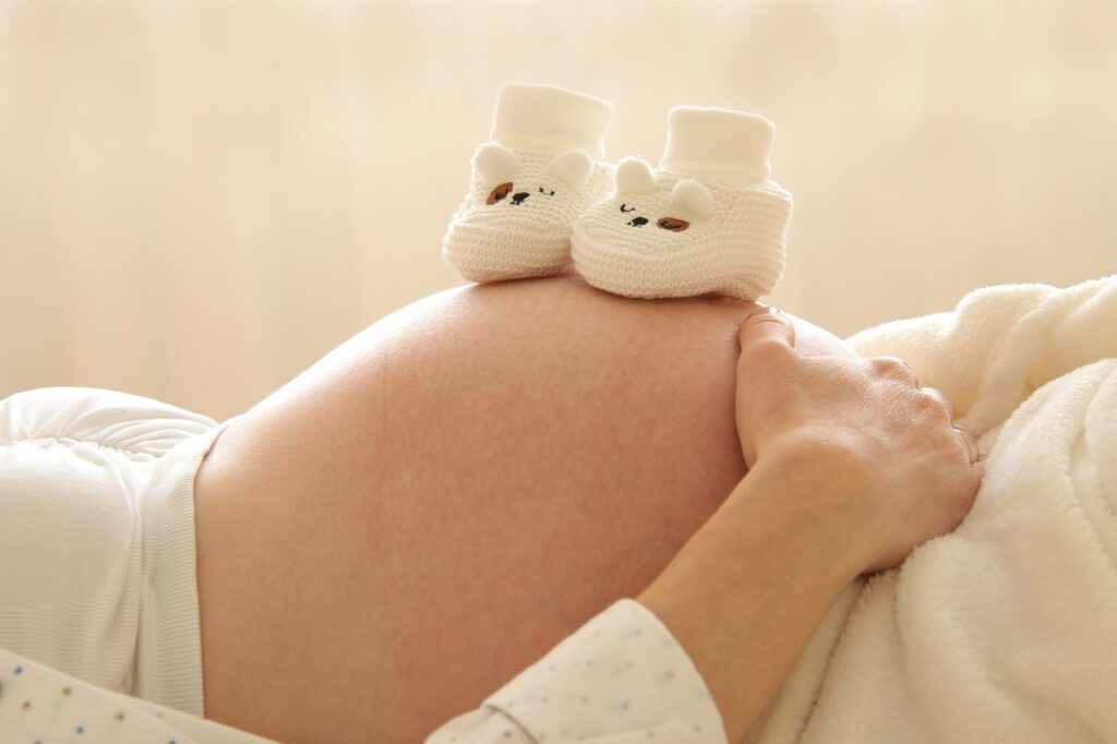 pregnant woman with two tiny shoes on her stomach